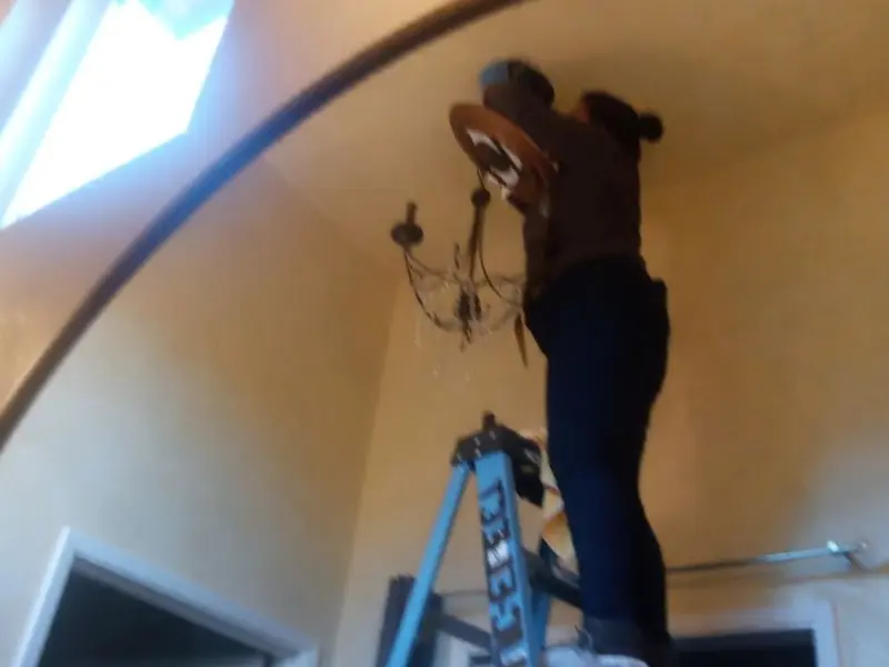 Electrician installing a chandelier in a Hugo residence